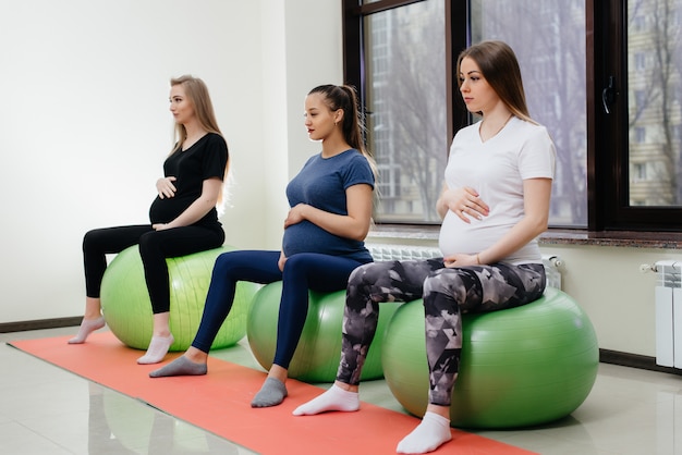 Un grupo de jóvenes madres embarazadas se dedican a Pilates y deportes de pelota en un gimnasio. Embarazada
