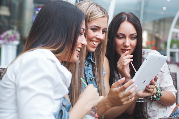 Grupo de jóvenes mujeres bonitas haciendo compras en línea en el café