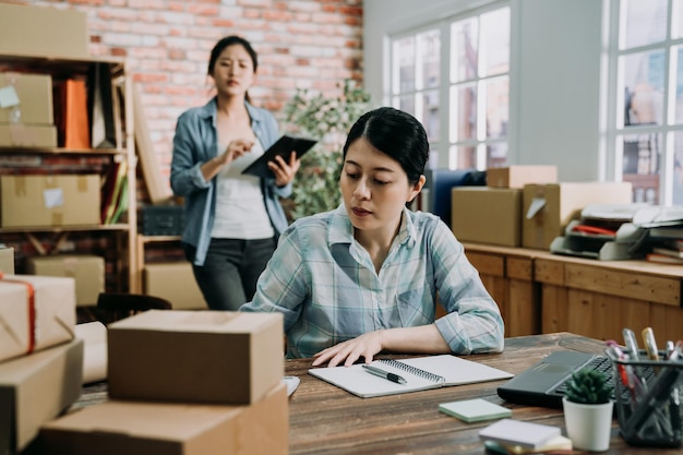 grupo de jóvenes mujeres hermosas casuales empresarias colegas dueños de negocios trabajan en la oficina con muchas cosas que hacer hoy. nota femenina nueva orden sentada en el escritorio con un compañero de trabajo caminando en el fondo.