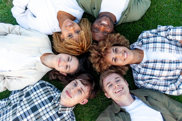 grupo de jóvenes multirraciales relajarse y acostarse juntos en la hierba en el parque y sonreír