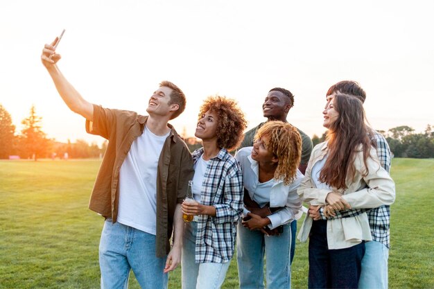 un grupo de jóvenes multirraciales se toman selfies con su teléfono inteligente y se toman fotos en el parque