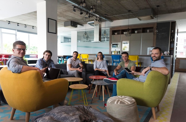 Foto el grupo de jóvenes en la oficina moderna tiene una reunión de equipo y una lluvia de ideas mientras trabaja en una computadora portátil y toma café