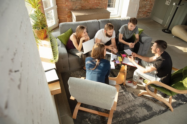 Grupo de jóvenes oficinistas caucásicos reunidos para discutir nuevas ideas. Reunión creativa. Trabajo en equipo y lluvia de ideas. Hombres y mujeres se reúnen en la oficina para planificar su trabajo futuro. Concepto de negocio.