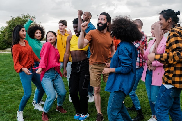 Grupo de jóvenes de origen multiétnico bailando juntos al aire libre