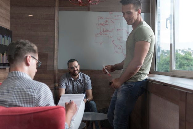 Foto el grupo de jóvenes en una pequeña oficina privada tiene una reunión de equipo y una lluvia de ideas mientras trabaja en una computadora portátil y una tableta
