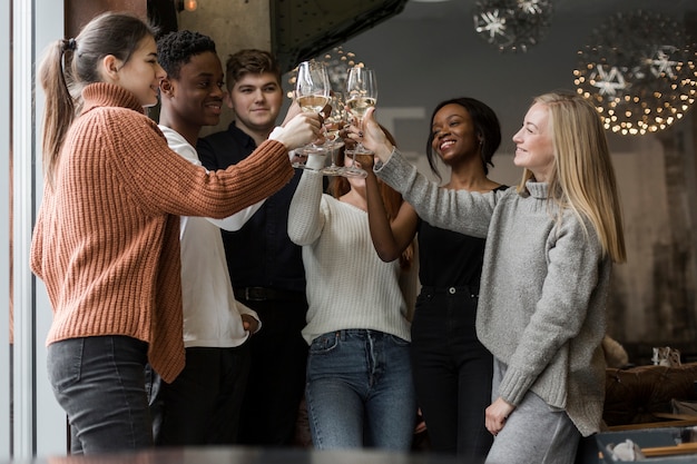 Grupo de jóvenes positivos brindando con vino