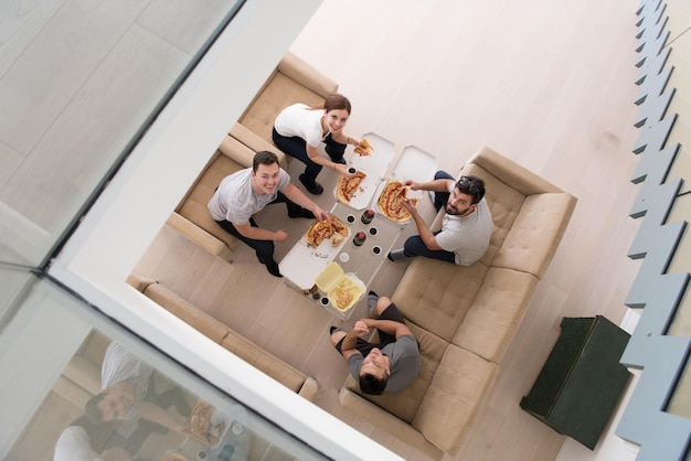 un grupo de jóvenes que pasan el tiempo alegremente mientras comen pizza en su villa de lujo