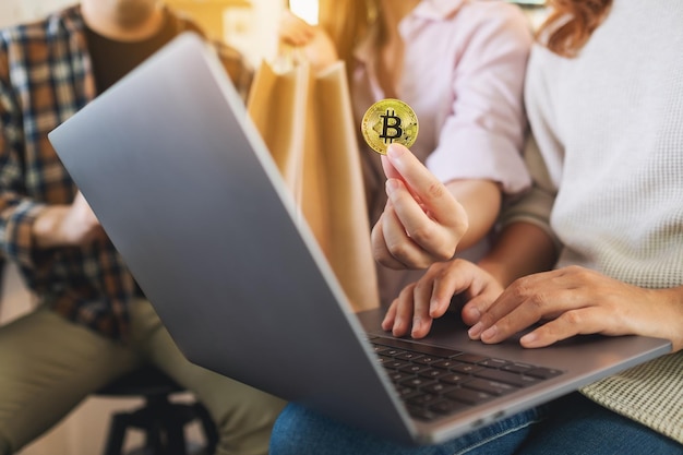 Grupo de jóvenes que usan laptop y bitcoin para comprar en línea juntos