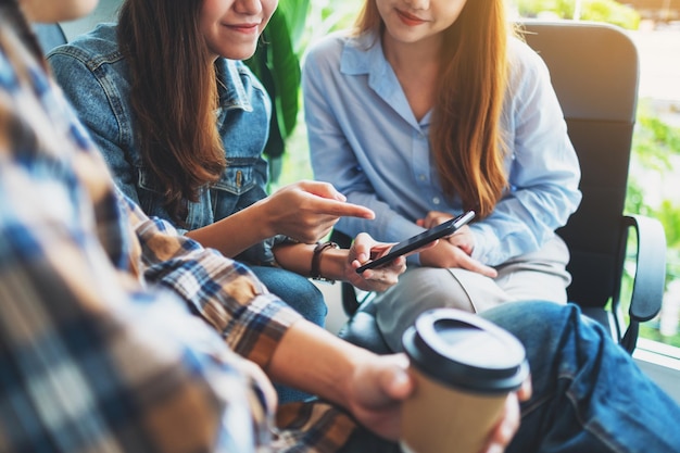 Grupo de jóvenes que usan el teléfono, hablando y tomando café juntos