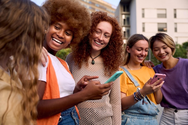 Grupo de jóvenes de raza mixta con teléfonos móviles entusiasman a los estudiantes usando dispositivos tecnológicos