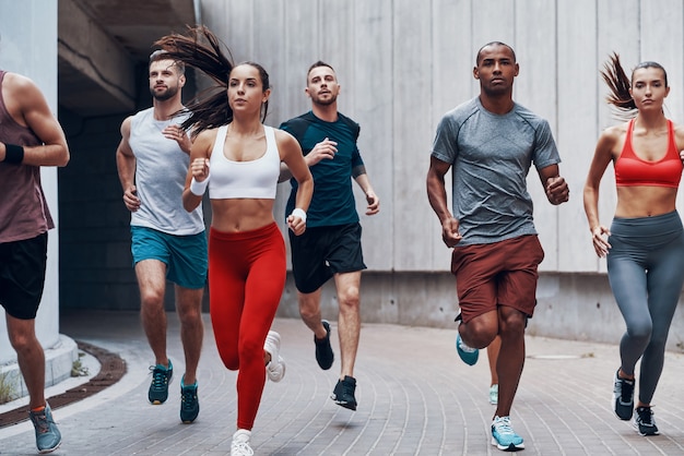 Grupo de jóvenes en ropa deportiva para correr mientras hace ejercicio al aire libre