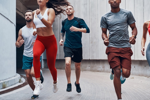 Grupo de jóvenes en ropa deportiva para correr mientras hace ejercicio al aire libre