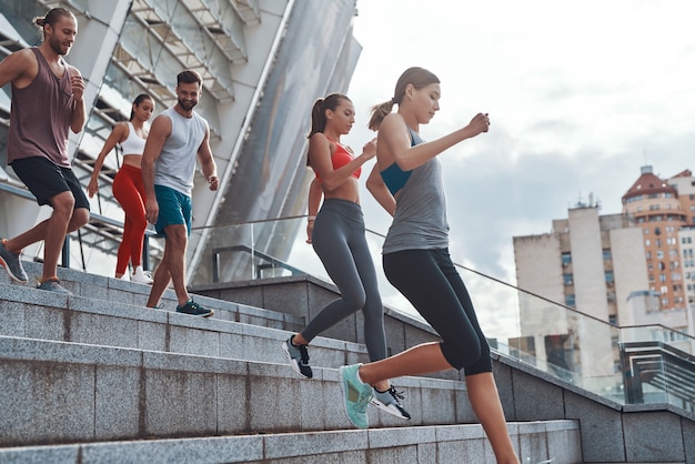 Grupo de jóvenes en ropa deportiva para correr mientras hace ejercicio en las escaleras al aire libre