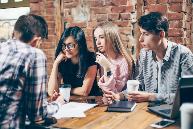 Grupo de jóvenes sentados en un café, tomando café y discutiendo nuevas ideas.