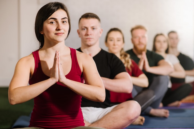 Un grupo de jóvenes sentados en pose de yoga uno detrás del otro