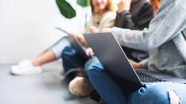 Un grupo de jóvenes sentados y usando una computadora portátil y una tableta digital juntos