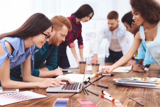 Grupo de jóvenes trabajan en equipo en una gran oficina brillante.