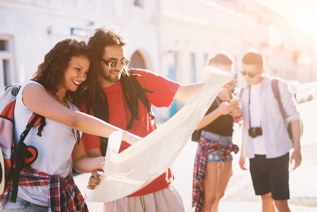 Foto grupo de jóvenes de vacaciones en una ciudad en busca de una dirección en un mapa.