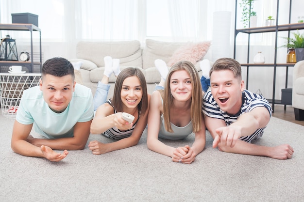 Grupo de jóvenes viendo la televisión. Amigos emocionales divirtiéndose y viendo el juego en el interior.