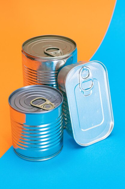 Foto un grupo de latas apiladas con bordes en blanco sobre fondo azul y naranja dividido