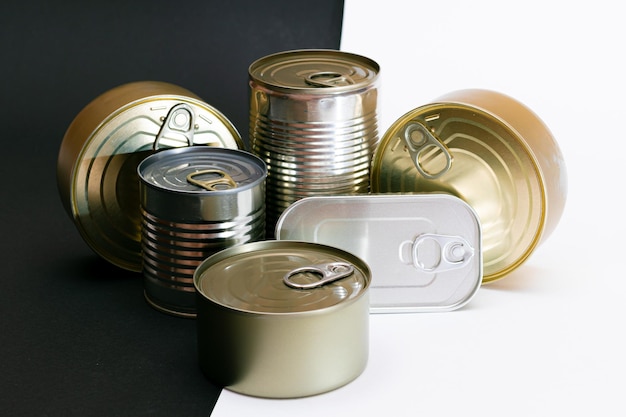 Un grupo de latas apiladas con bordes en blanco sobre fondo blanco y negro dividido