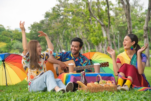 Foto grupo lgbtq sentado cantando y comiendo en el parque y tomando fotos concepto de estilo de vida happilylgbtq