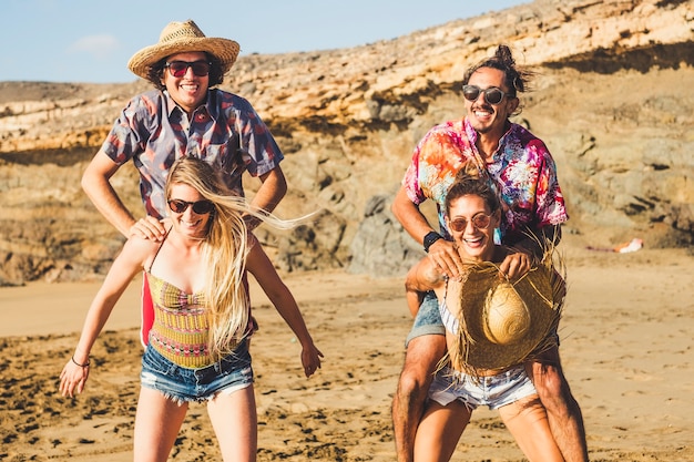 Grupo loco de gente caucásica amigos hombres y mujeres jugando juntos en la playa en vacaciones