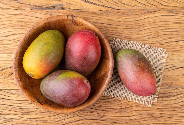 Un grupo de mangos maduros sobre una mesa de madera