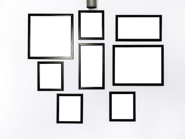 Grupo de marcos de fotos de maquetas. Cuadro cuadrado blanco con maqueta de marco negro colgando en el fondo de la pared blanca.