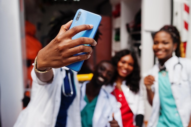 Grupo de médicos africanos del equipo de emergencia de la ambulancia paramédica haciendo selfie por teléfono.