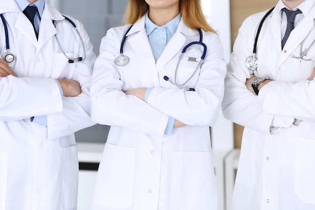 Grupo de médicos modernos de pie como equipo con los brazos cruzados en el primer plano de la oficina del hospital