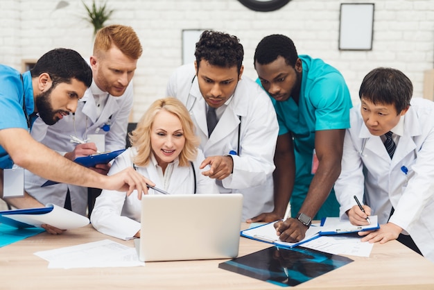 Foto un grupo de médicos observa algo en la computadora portátil.