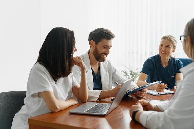 Grupo de médicos sentados en la mesa de reuniones en la sala de conferencias durante el seminario médico