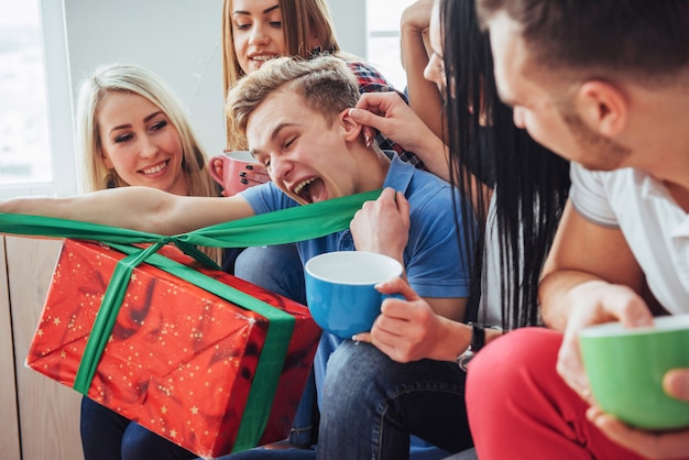 Grupo de mejores amigos en la fiesta. gente sonriente y alegre sentada en las escaleras una taza de café saluda el cumpleaños, gran regalo