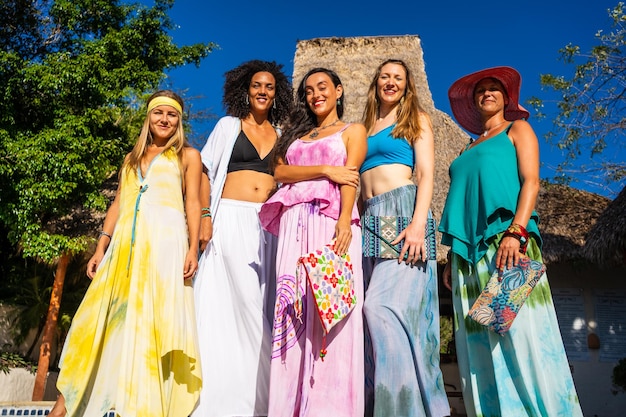 Grupo de modelos de pie con coloridos vestidos largos al aire libre