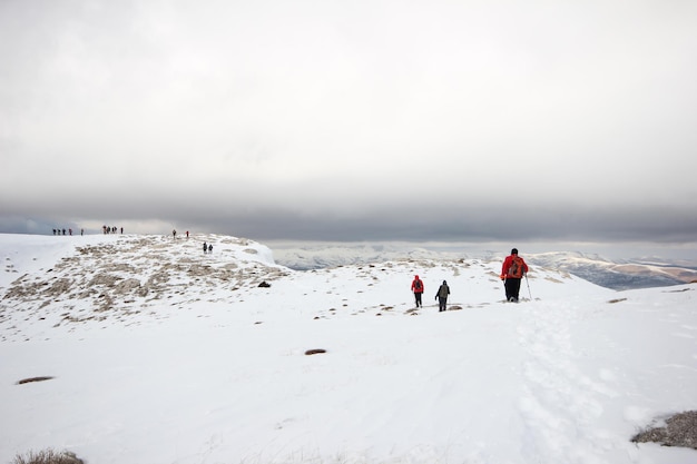 Grupo de montañeros caminando por las montañas cubiertas de nievexAxA