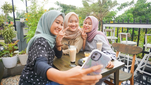 Grupo de mujer asiática hijab selfie en café con un amigo