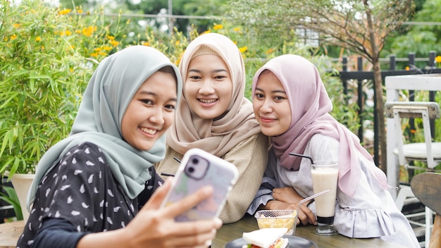 Grupo de mujer asiática hijab selfie en café con un amigo