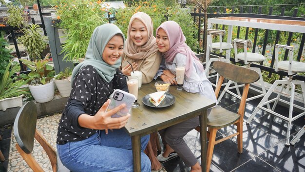 Grupo de mujer asiática hijab selfie en café con un amigo