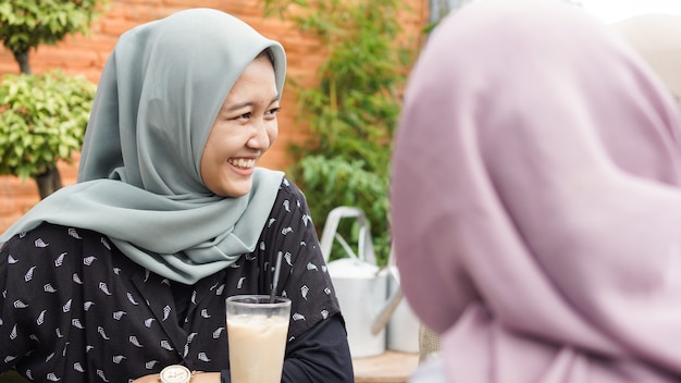 Grupo de mujer asiática hijab smilling en café con un amigo