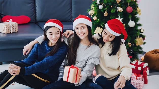 Grupo de mujer hermosa asiática con cajas de regalo. Cara sonriente en la habitación con decoración de árboles de Navidad