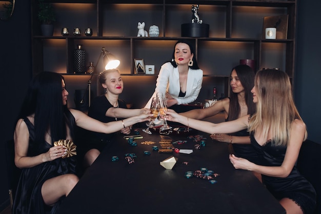 Grupo de mujer sexy joven de moda disfrutando jugando al póquer y bebiendo champán