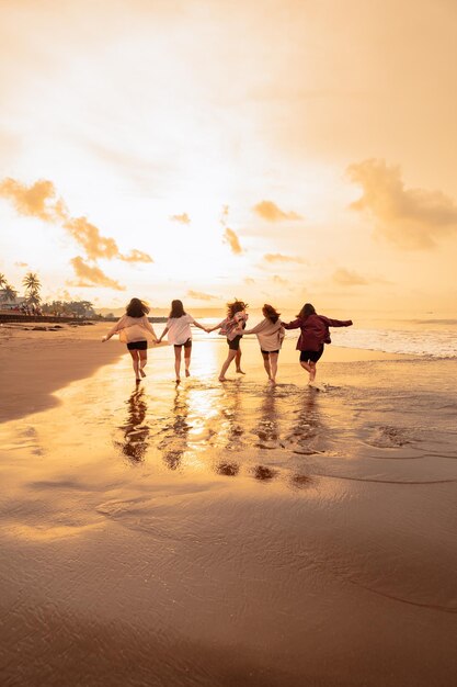 Un grupo de mujeres asiáticas corre felizmente con sus amigos en la playa