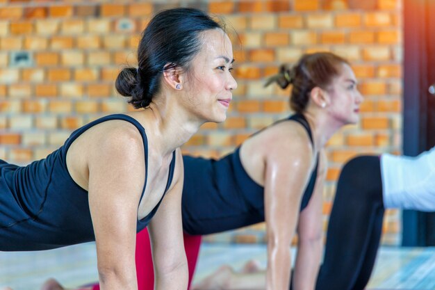 Grupo de mujeres asiáticas haciendo yoga namaste plantean