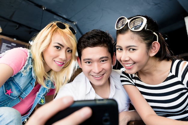 Grupo de mujeres asiáticas y hombre haciendo selfie con teléfono