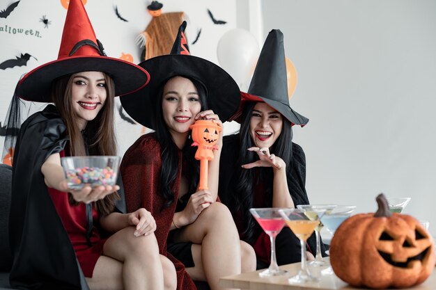 Grupo de mujeres asiáticas jóvenes en traje de bruja celebrar fiesta en la sala para el tema de Halloween en casa. Pandilla adolescente tailandés con celebrar la fiesta de Halloween con una sonrisa. Concepto de fiesta de Halloween en casa.