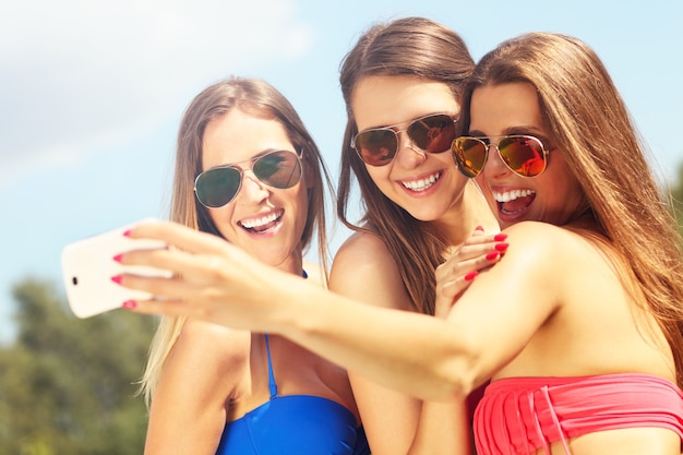 Grupo de mujeres en bikini tomando selfie al aire libre