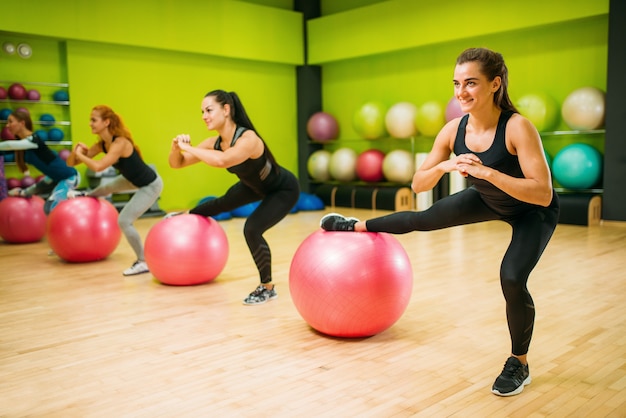 Grupo de mujeres con bolas grandes, ejercicio en forma, entrenamiento físico. Trabajo en equipo de deporte femenino en el gimnasio. Clase aeróbica