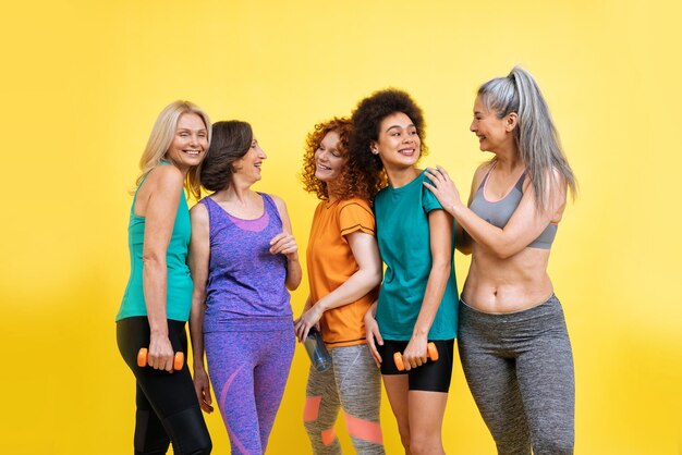 Grupo de mujeres con diferente cuerpo, edad y etnia haciendo deporte. Modelos femeninas con ropa deportiva divirtiéndose en el gimnasio. Concepto sobre positividad corporal, autoaceptación y estilo de vida