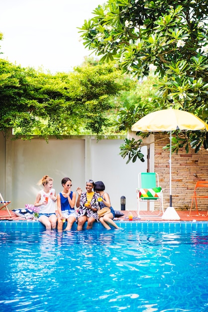 Grupo de mujeres diversas sentadas junto a la piscina.